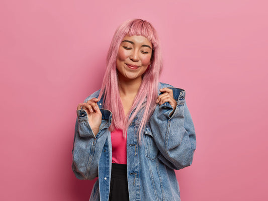 Mujer sonriendo con su pelo de color rosa, feliz por revivir el pelo decolorado